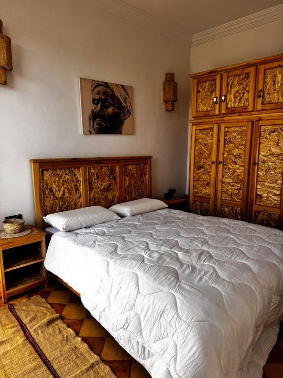 ein Schlafzimmer mit einem großen weißen Bett mit Holzkopfteil in der Unterkunft Palais Taroudant in Taroudant