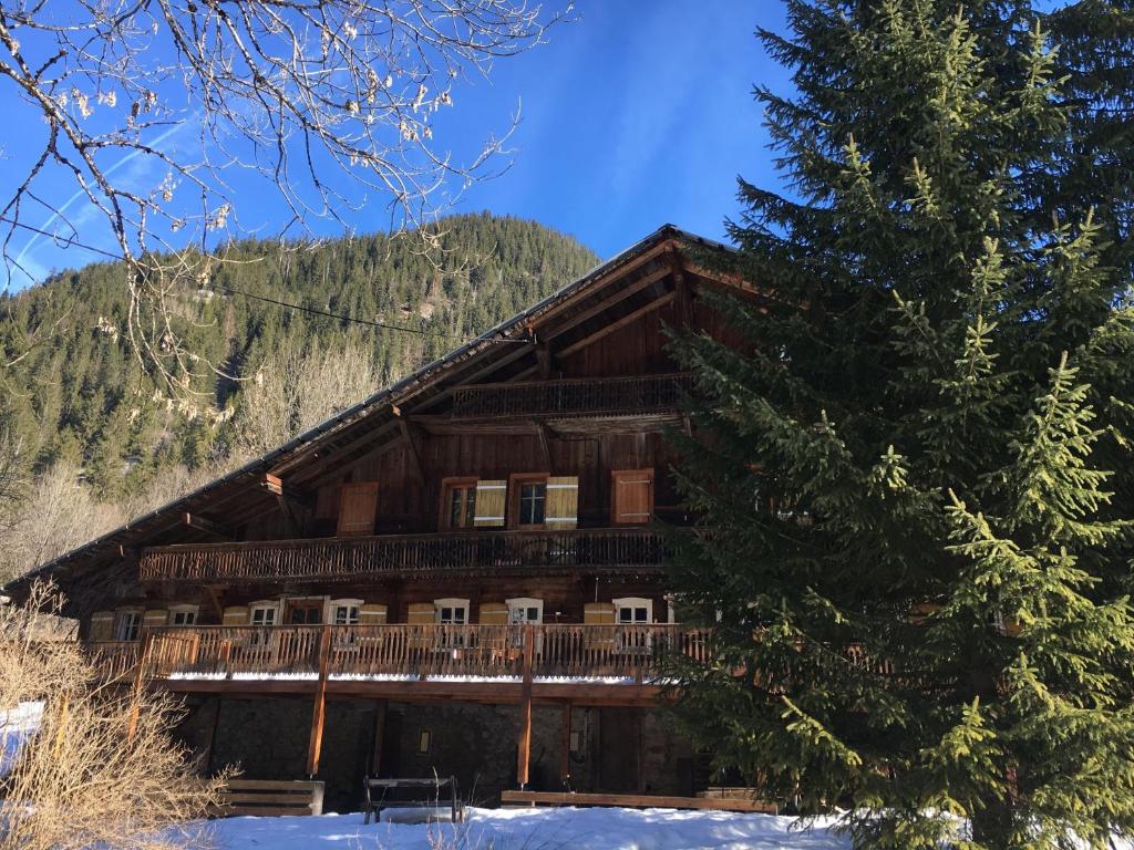 a log cabin in the snow next to a tree at Chalet Suvay in La Chapelle-dʼAbondance