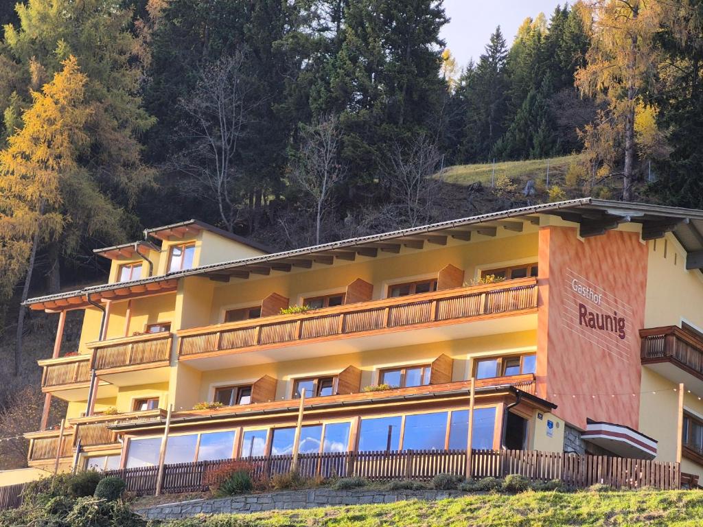 un gran edificio amarillo en una colina con árboles en Hotel Restaurant Raunig, en Bad Kleinkirchheim