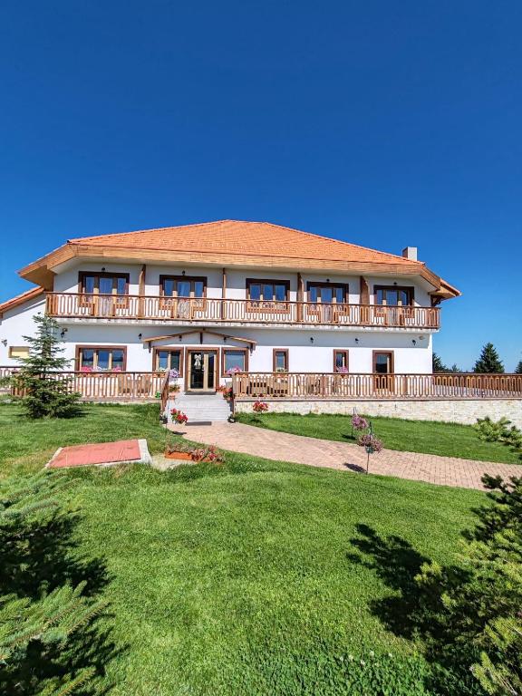 a large white house with a large yard at Pensiunea Roua Brazilor Mărișel in Mărişel