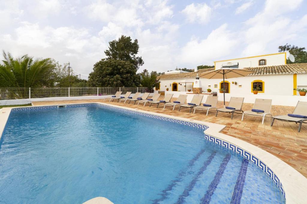 a swimming pool with chairs and a house at Villa Monte Domingos Simoes in Sesmarias