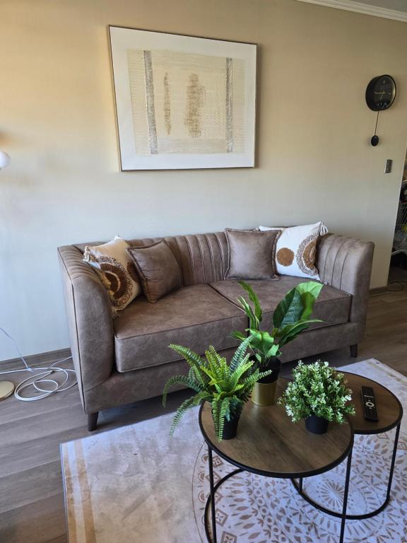 a living room with a brown couch and two tables at Rancagua Lujo y comodidad Depto con Piscina y Estacionamiento in Rancagua