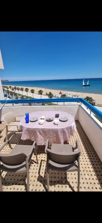 a balcony with a table and chairs and the beach at Vista bella luxurious apartment in Martil