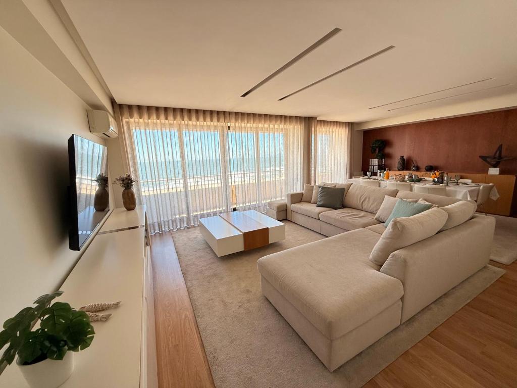 a living room with a couch and a tv at Beachouse Pvz - Seafront in Póvoa de Varzim