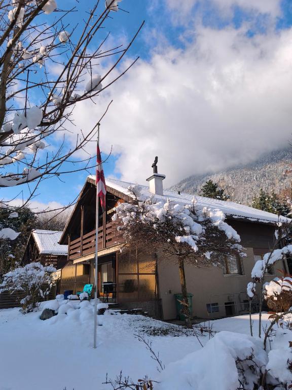 因特拉肯Chalet Rose - Einfamilienhaus的雪地里，屋顶上挂着国旗的房子