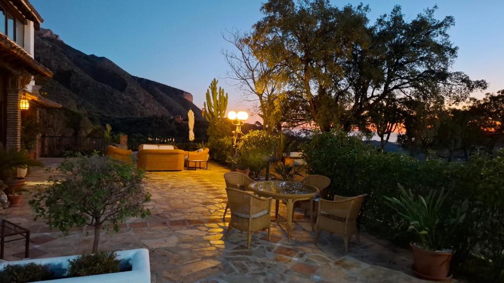 a patio with a table and chairs at night at Hotel Rural Los Jarales in Istán