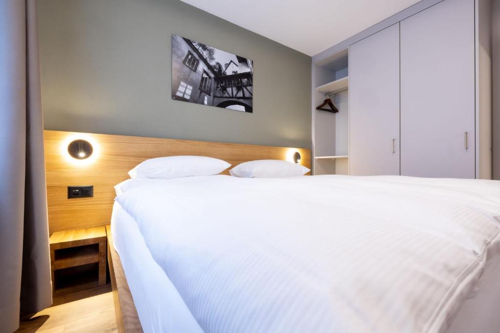 Un dormitorio con una gran cama blanca con cabecero de madera. en Hotel R5 Budget - Chur, en Chur