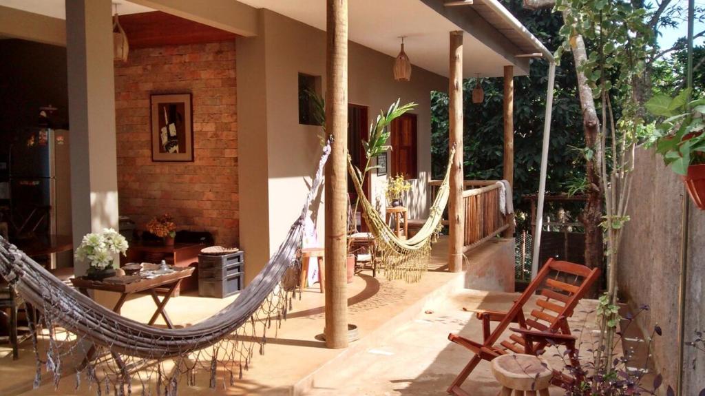 a patio with a hammock and a table and chairs at Casa hibiscus in Itacaré