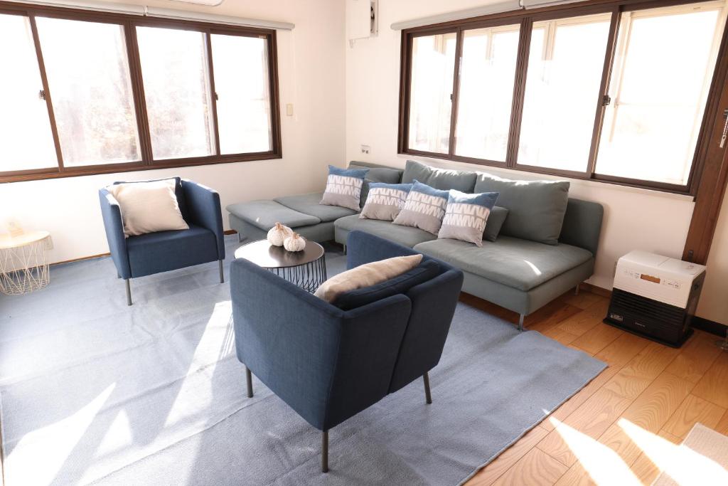 Una sala de estar con un sofá y sillas y ventanas. en Forest and Stars Akakura Sauna, en Myoko