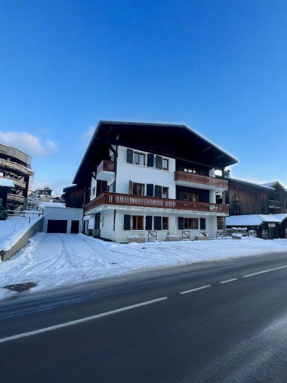 a white building with a black roof on the side of a road at Résidences Delavay La Cordée in Les Gets