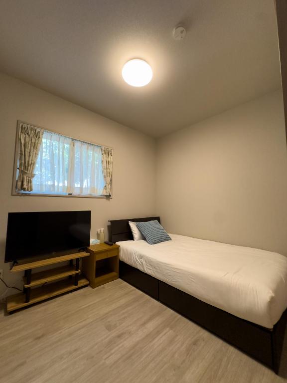 a room with two beds and a flat screen tv at 久松の宿 in Miyako-jima