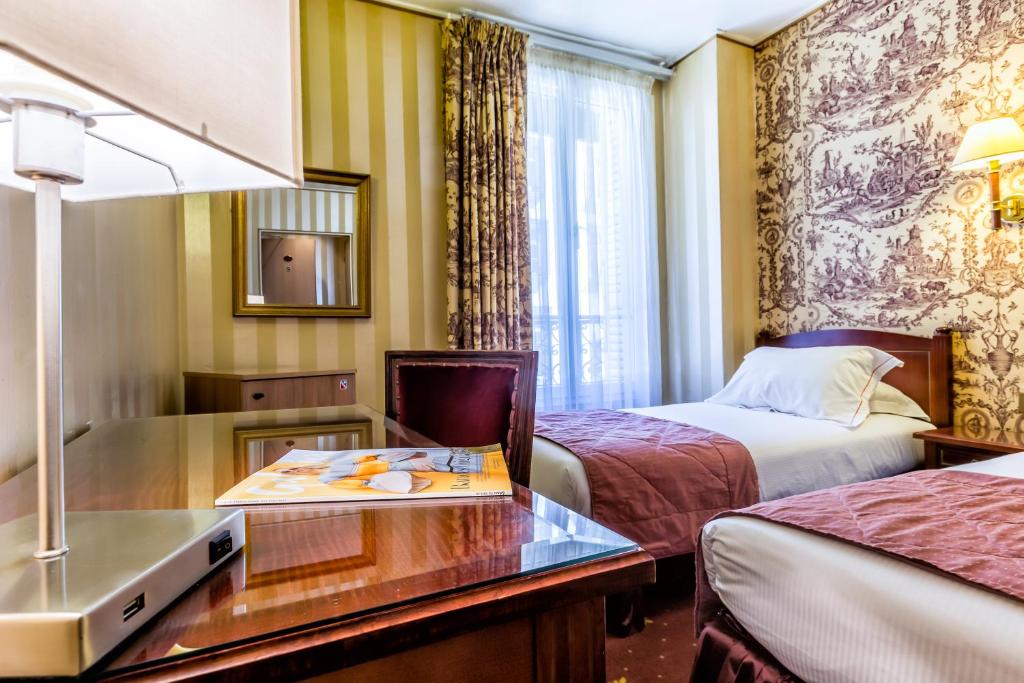 a hotel room with two beds and a desk at Hotel Regence Paris in Paris
