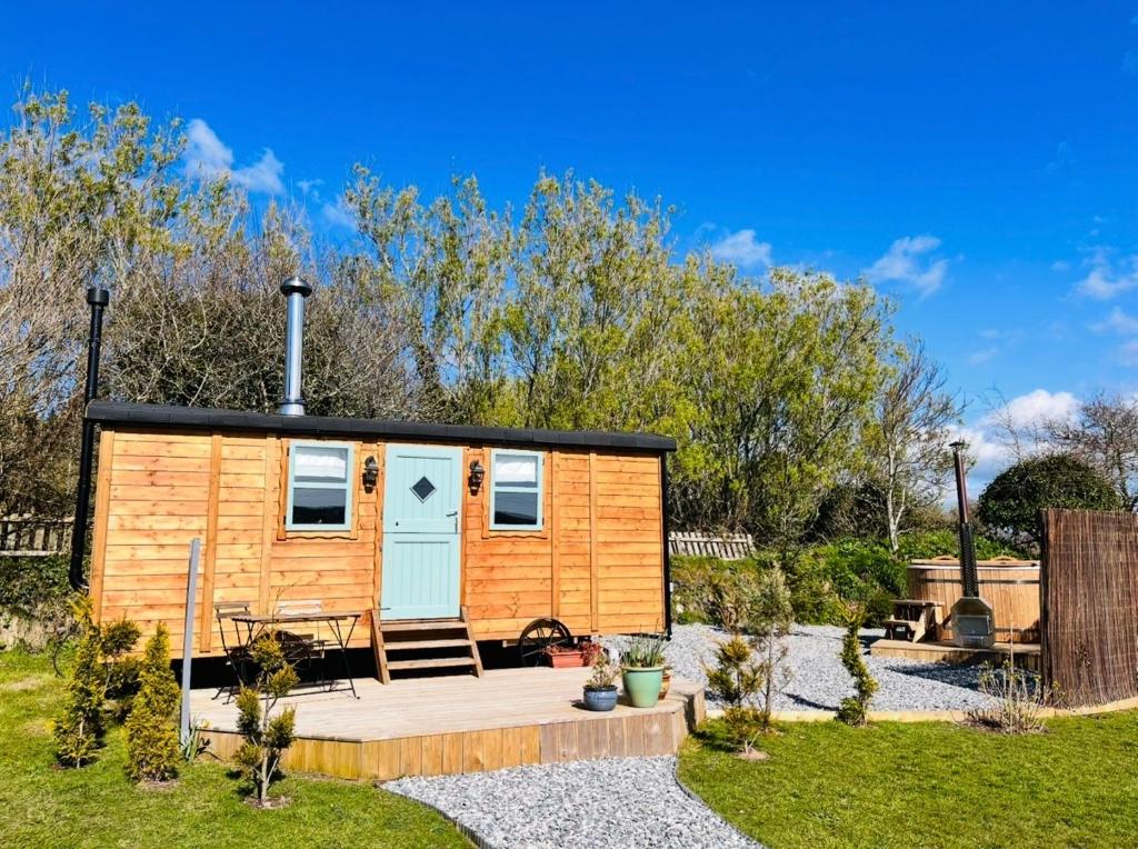 a tiny house with a deck in a garden at Cornwall Shepherds Hut - Hot Tub & Cosy Log Burner in Saint Day