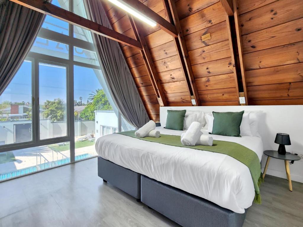 a bedroom with a large bed with wooden ceilings at Salt Boutique Guest House in Bloubergstrand