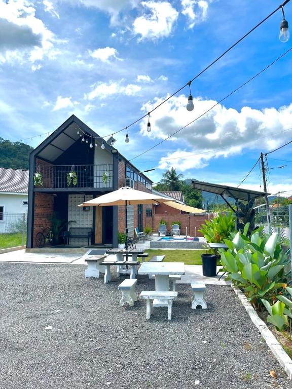 un groupe de tables de pique-nique et un parasol devant un bâtiment dans l'établissement Kurie Redbrick House, à Balik Pulau