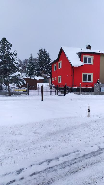 une maison rouge avec une clôture dans la neige dans l'établissement Chalupa Maršovice, à Nové Město na Moravě