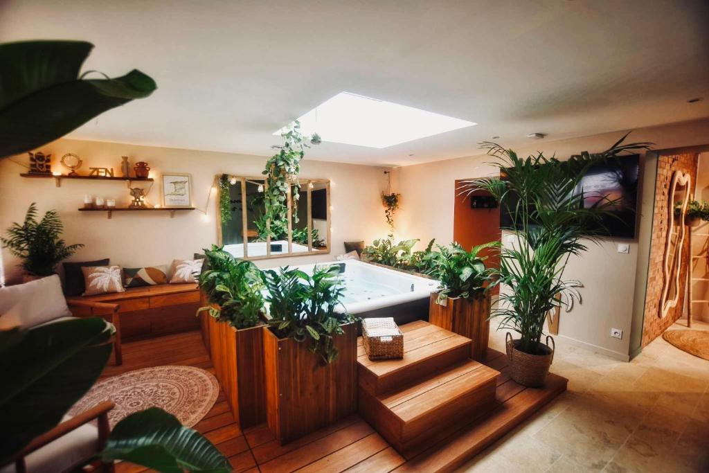 Habitación grande con bañera con plantas. en Trinidad Vibes - Suite and Spa - Petit déjeuner inclus, en Aire-sur-la-Lys