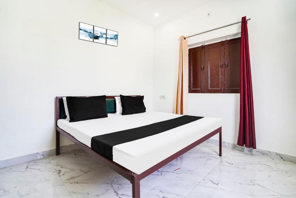 Una cama en una habitación blanca con ventana. en Hotel O The Moon, en Bareilly