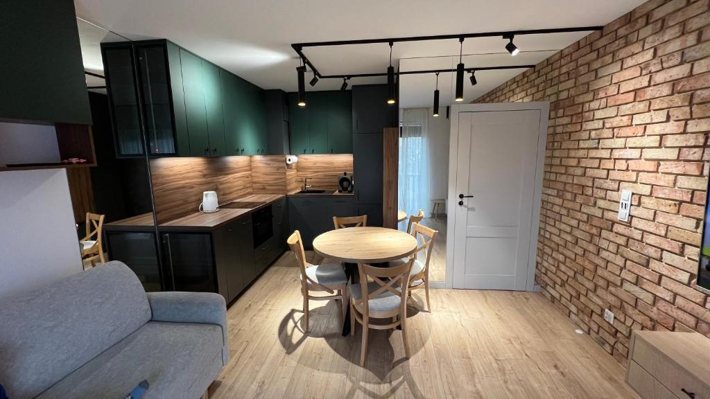 a kitchen and dining room with a table and a brick wall at REMI Apartament Biotura in Gdańsk