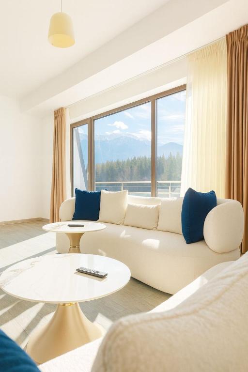 a living room with a white couch and a large window at Luxury Penthouse-Poiana Brasov in Poiana Brasov