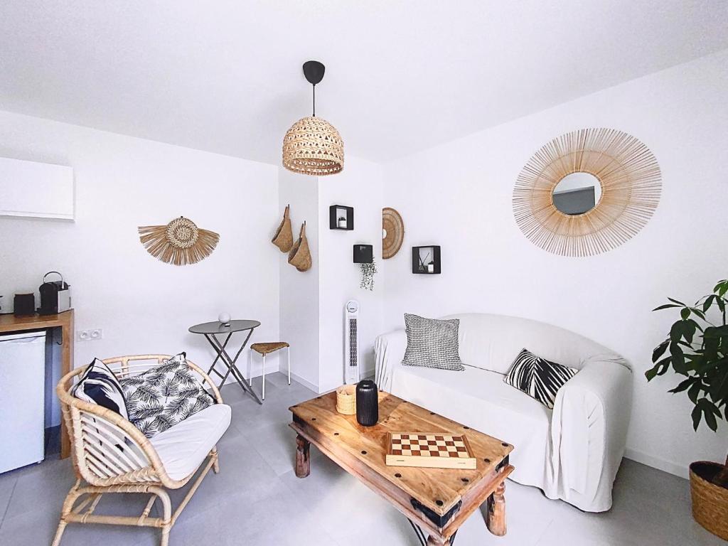 拉佩讷叙尔于沃讷Le Romarin Bas de villa T2 avec jardin et parking au pied de la Forêt的客厅里有一张白色的沙发和一张桌子