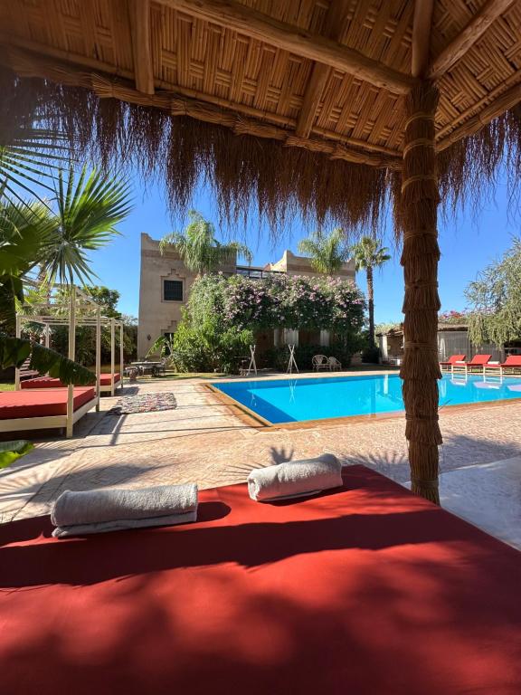 a bed under a pavilion with a swimming pool at Villa Atika in El Bougaria
