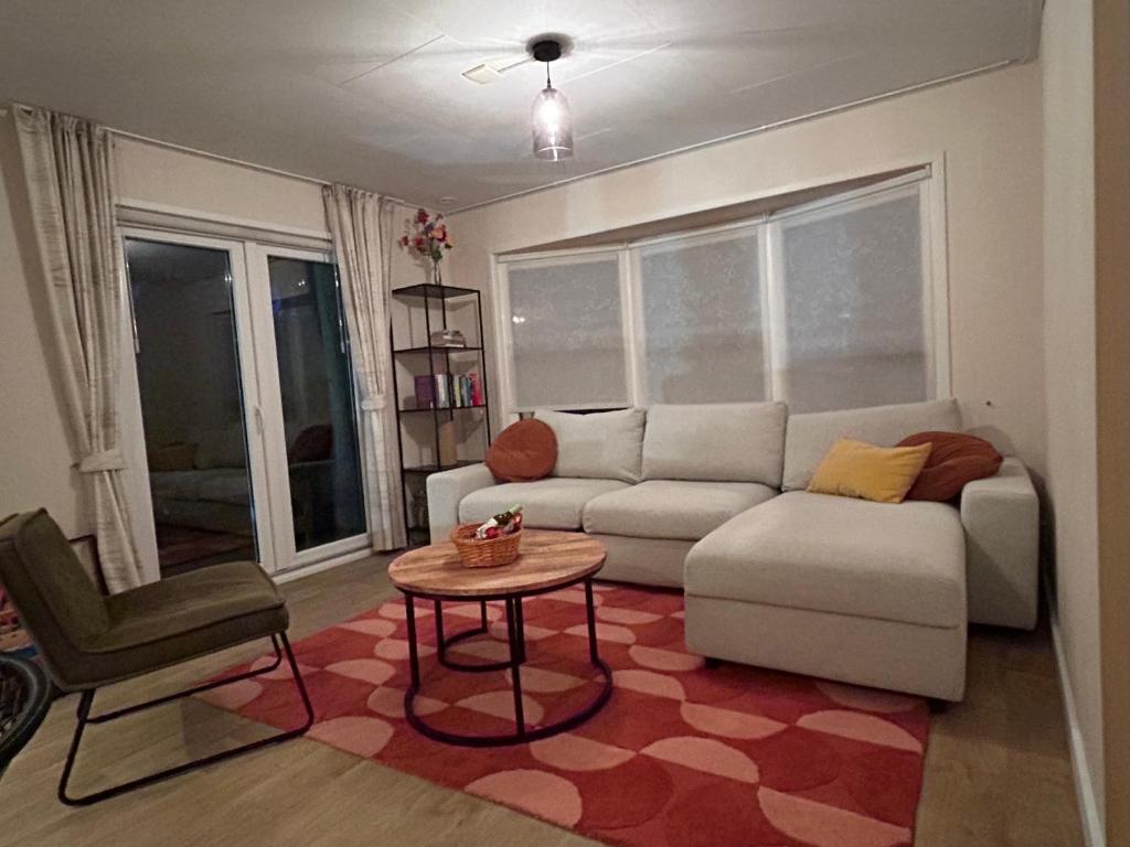 ein Wohnzimmer mit Sofa und Tisch in der Unterkunft Fijne caravan midden in de bossen van de Veluwe in Hoenderloo