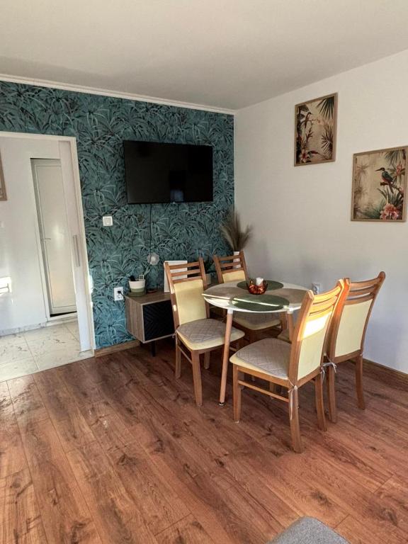 a dining room with a table and chairs and a television at White House Apartments - Forest in Haskovo