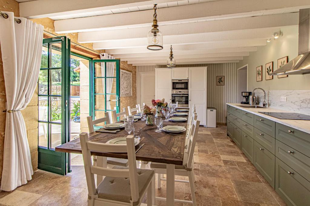 Un comedor con una mesa y sillas en una cocina. en La Mouy - Périgord Noir - Farmhouse with pool, en Mauzens-et-Miremont