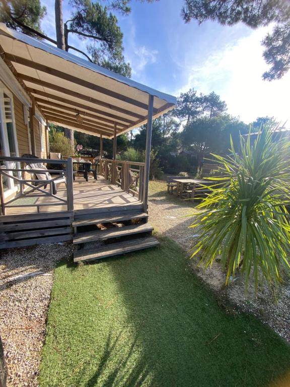 eine überdachte Terrasse mit Picknicktisch und Palme in der Unterkunft Tohapi camping Atlantic Club in Montalivet-les-Bains
