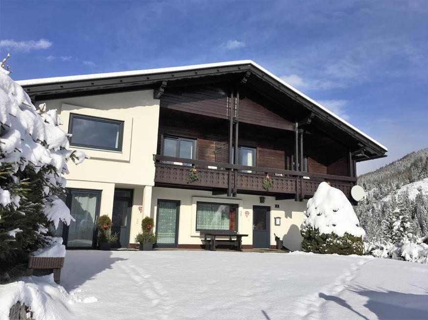 een huis in de sneeuw met een bank voor bij Appartement Latschen - Ferienhaus in Bad Kleinkirchheim