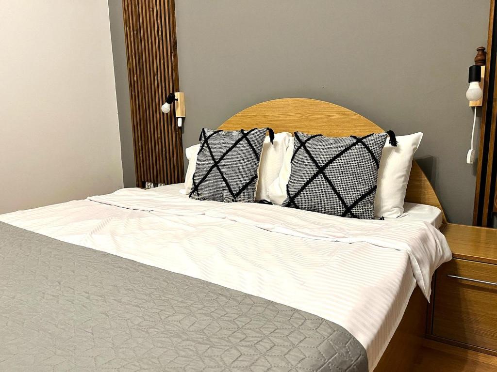 a bed with a wooden headboard and white sheets and pillows at 5th Forest Villa – Family Retreat, Garden & BBQ in Predeal