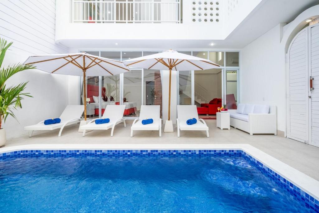 een zwembad met stoelen en parasols in een huis bij Luxury minimalist villa The Toy in Kerobokan