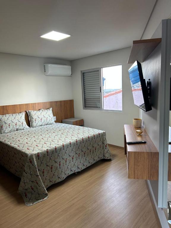 um quarto com uma cama e uma televisão em Kitnet cobertura Centro Bom Despacho em Bom Despacho