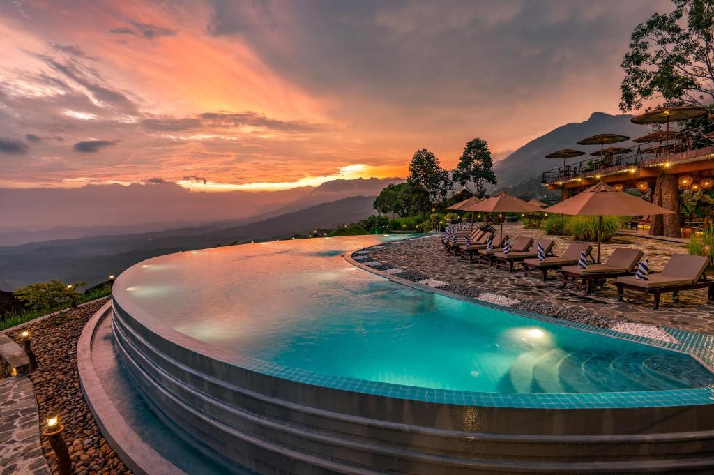 ein Pool in einem Resort mit Stühlen und einem Sonnenuntergang in der Unterkunft Dream Cliff Mountain Resort in Haputale
