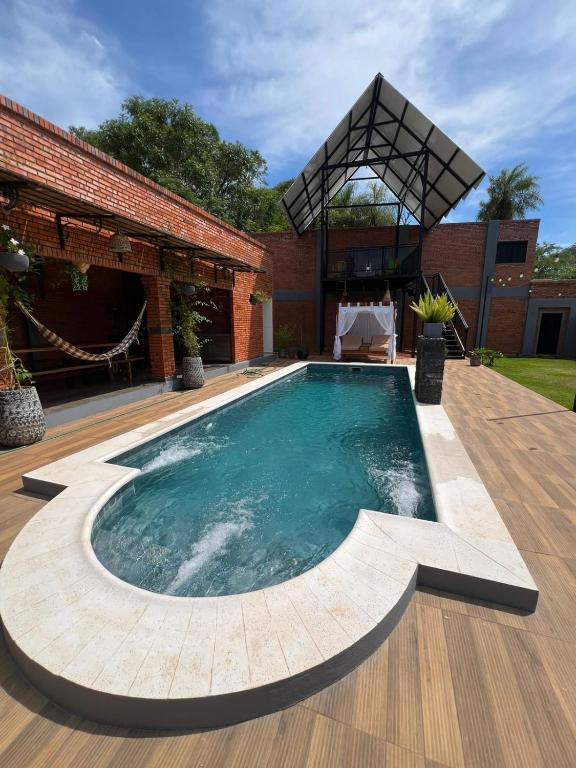 ein Schwimmbad mit Holzterrasse und ein Gebäude in der Unterkunft Casa Quinta Jurumi de La Mala Junta in Atyrá