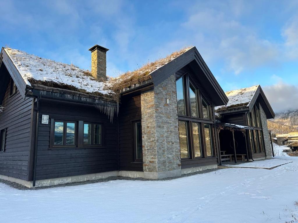 a house in the snow with a roof at Myrkdalen Lodge II, luxury family cabin in Helgatun