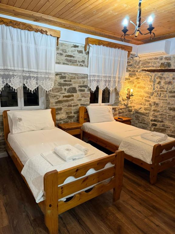 Dos camas en una habitación con pared de piedra. en Hotel Drasa, en Gjirokastra