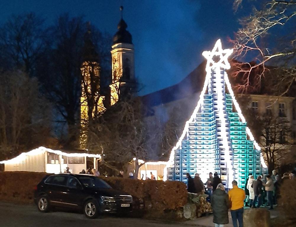 un grand arbre de Noël devant un bâtiment dans l'établissement Ferienwohnung KIostermühle Irsee - Parkplätze, Spielplatz, Biergarten, Badesee, E-Auto Ladepunkt, à Irsee