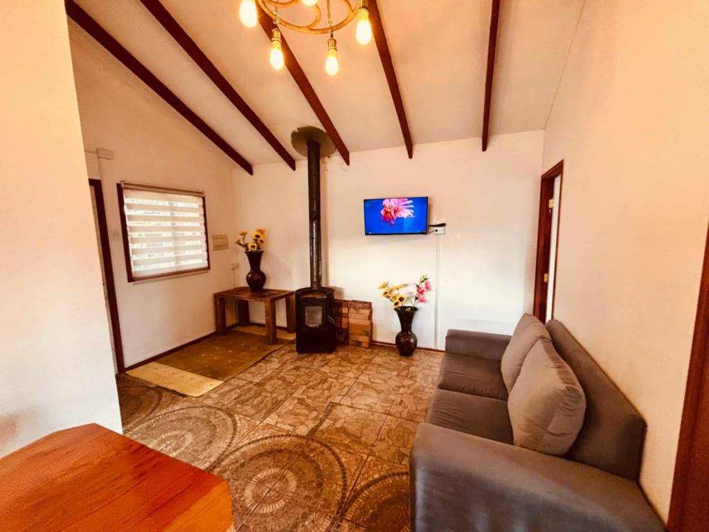 ein Wohnzimmer mit Sofa und Fernseher in der Unterkunft cabañas fariña in Llanquihue