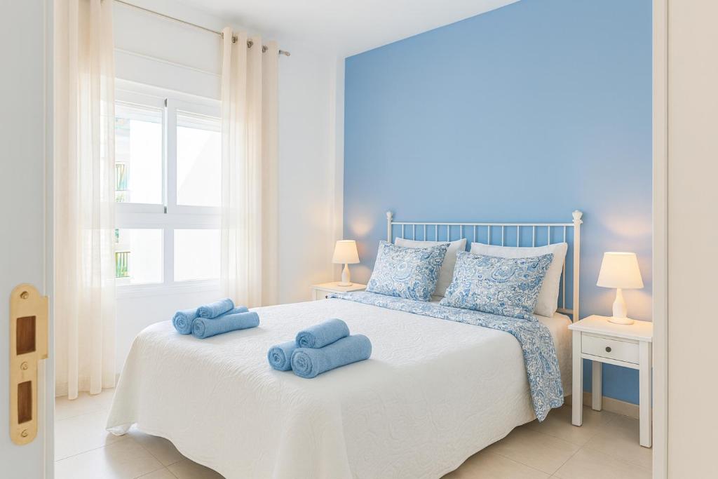 a bedroom with a white bed with blue towels on it at Mar Airport-Park by Babiniliving in Costa de Antigua