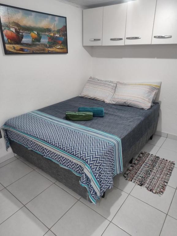 a bed with a blue and white blanket on it at Espaço inteiro-Praia de Barequeçaba - São Sebastião -SP in São Sebastião