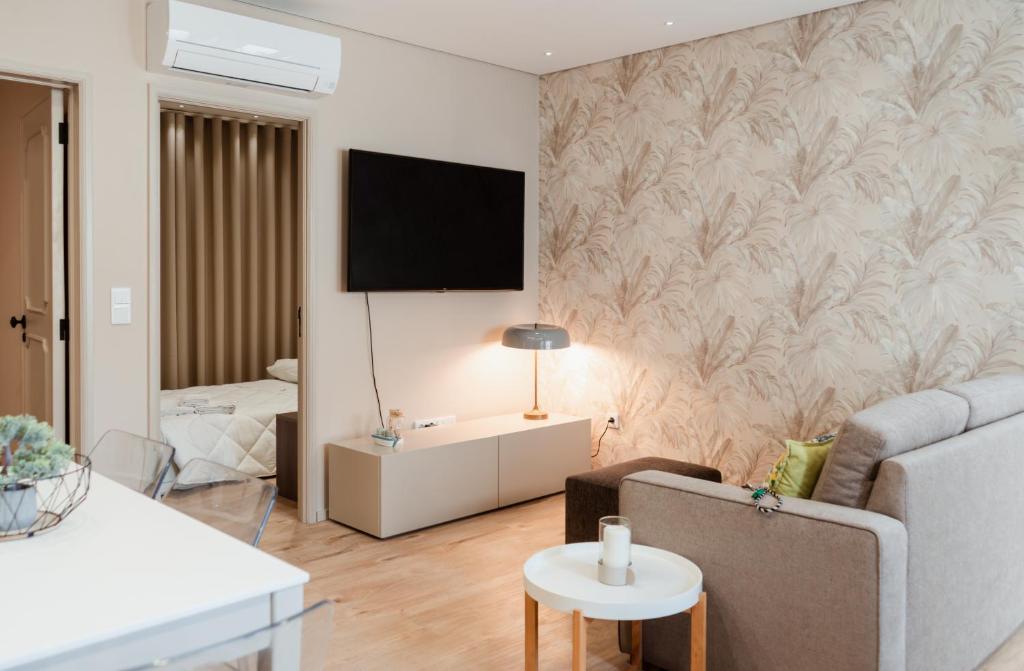 Una sala de estar con un sofá y un televisor en una pared. en Rua Fraga - Os Maias, en Vila do Conde
