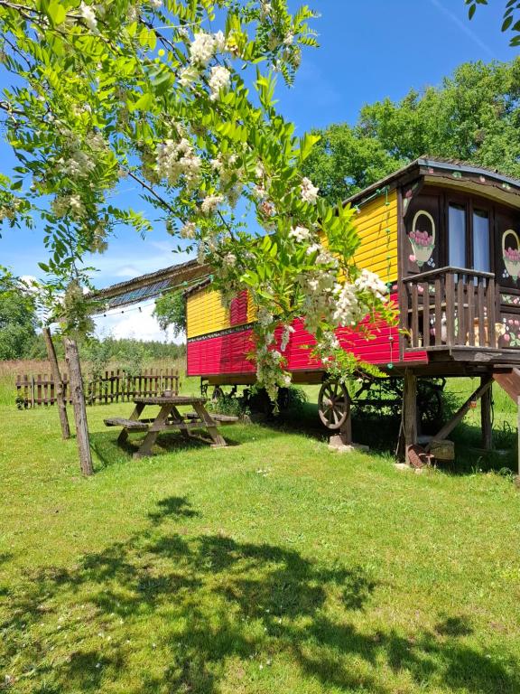 Ein neben einem Picknicktisch geparkter Eisenbahnwaggon in der Unterkunft Roulotte Belle des Prés in Sigalens