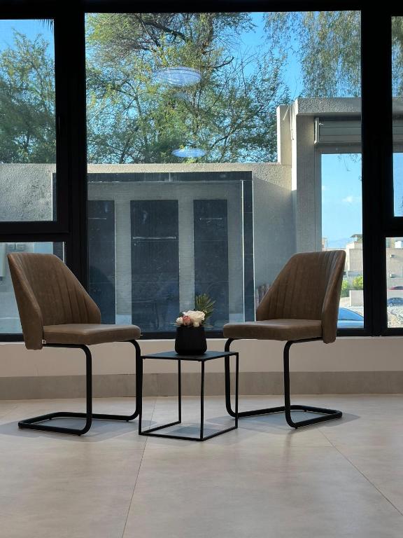 two chairs and a table in a room with windows at Alwadi view شرفة الوادي in Nizwa