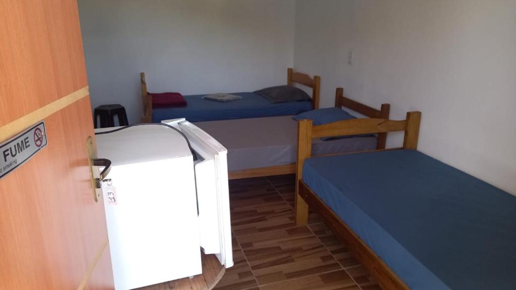Cette petite chambre comprend deux lits et un réfrigérateur. dans l'établissement Pousada Doce Lar, à Camanducaia