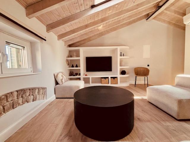 a living room with a table and a tv at L'Atelier TOP LOCATION in Corfu
