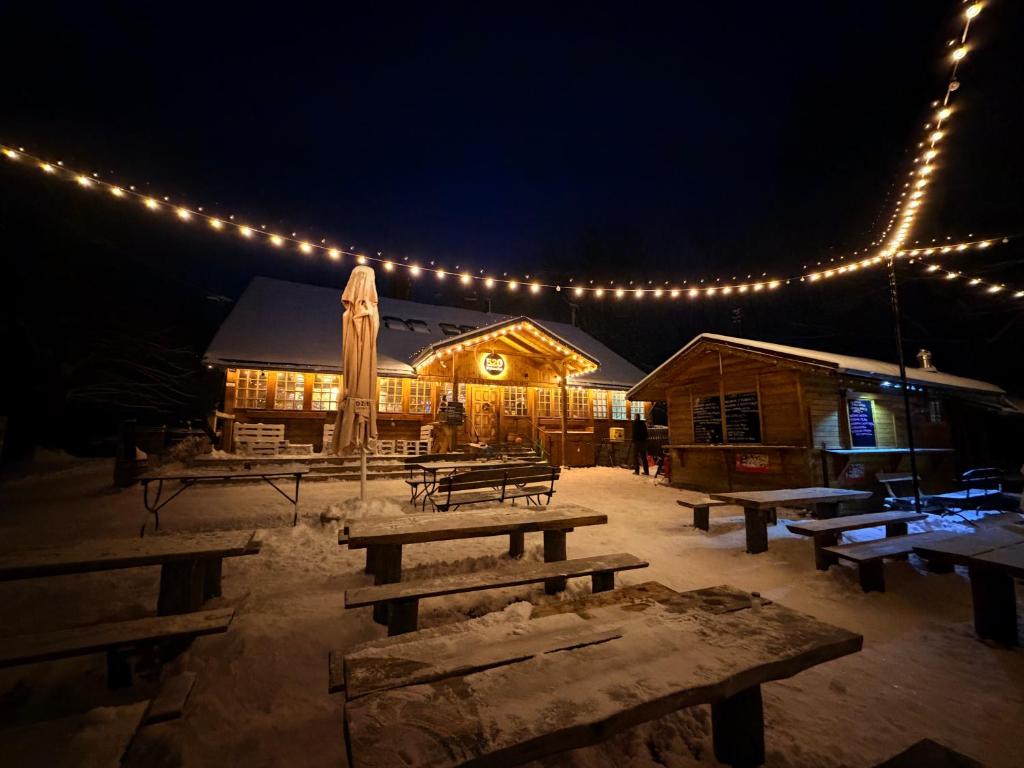 un groupe de tables de pique-nique devant un bâtiment illuminé dans l'établissement Gospoda Dębowiec520, à Bielsko-Biała