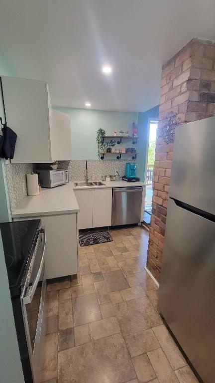 een keuken met witte kasten en een tegelvloer bij Quarto encantador in Nha Trang