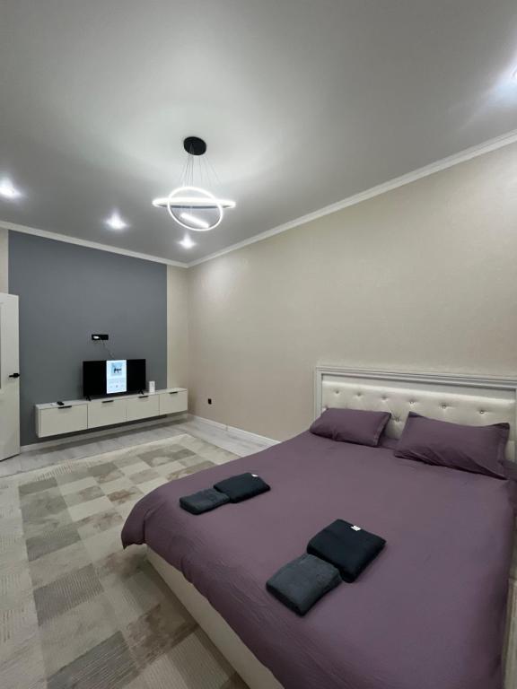 Квартира في Taldykolʼ: غرفة نوم مع سرير أرجواني كبير وتلفزيون بشاشة مسطحة